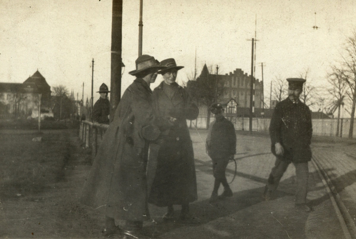 Two British nurses sightseeing in Cologne, Germany, while locals and a New Zealand soldier look on.